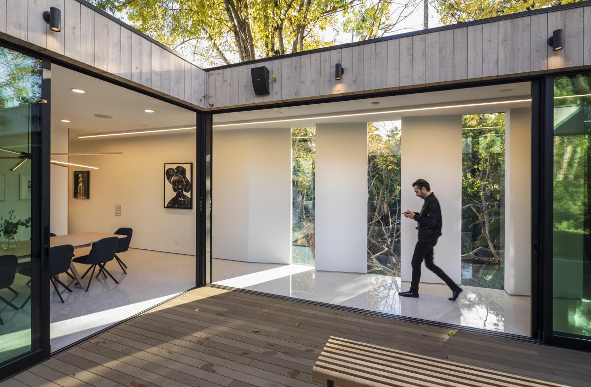 Dan Brunn walks past the floor-to-ceiling glass doors that open the outdoor terrace to the rest of the home.