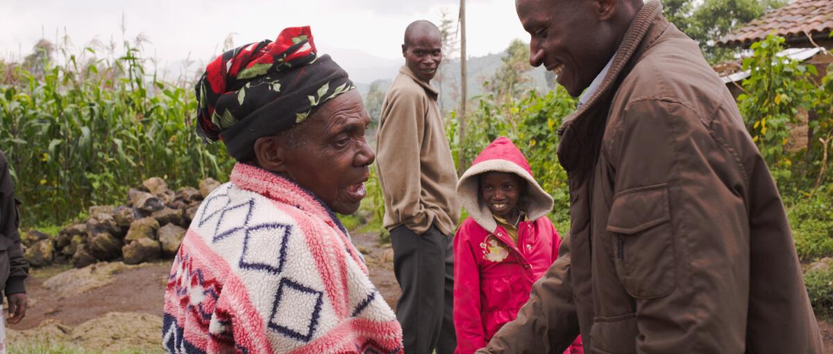 A man talks with an older woman against a cornfield