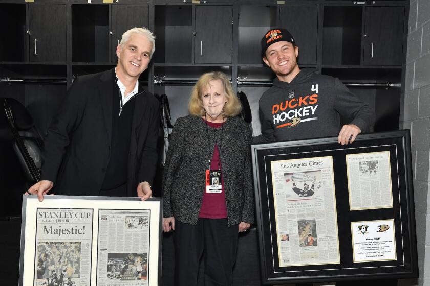The Kings' Luc Robitaille and Ducks' Cam Fowler present Times columnist Helene Elliott with frames copies of her work