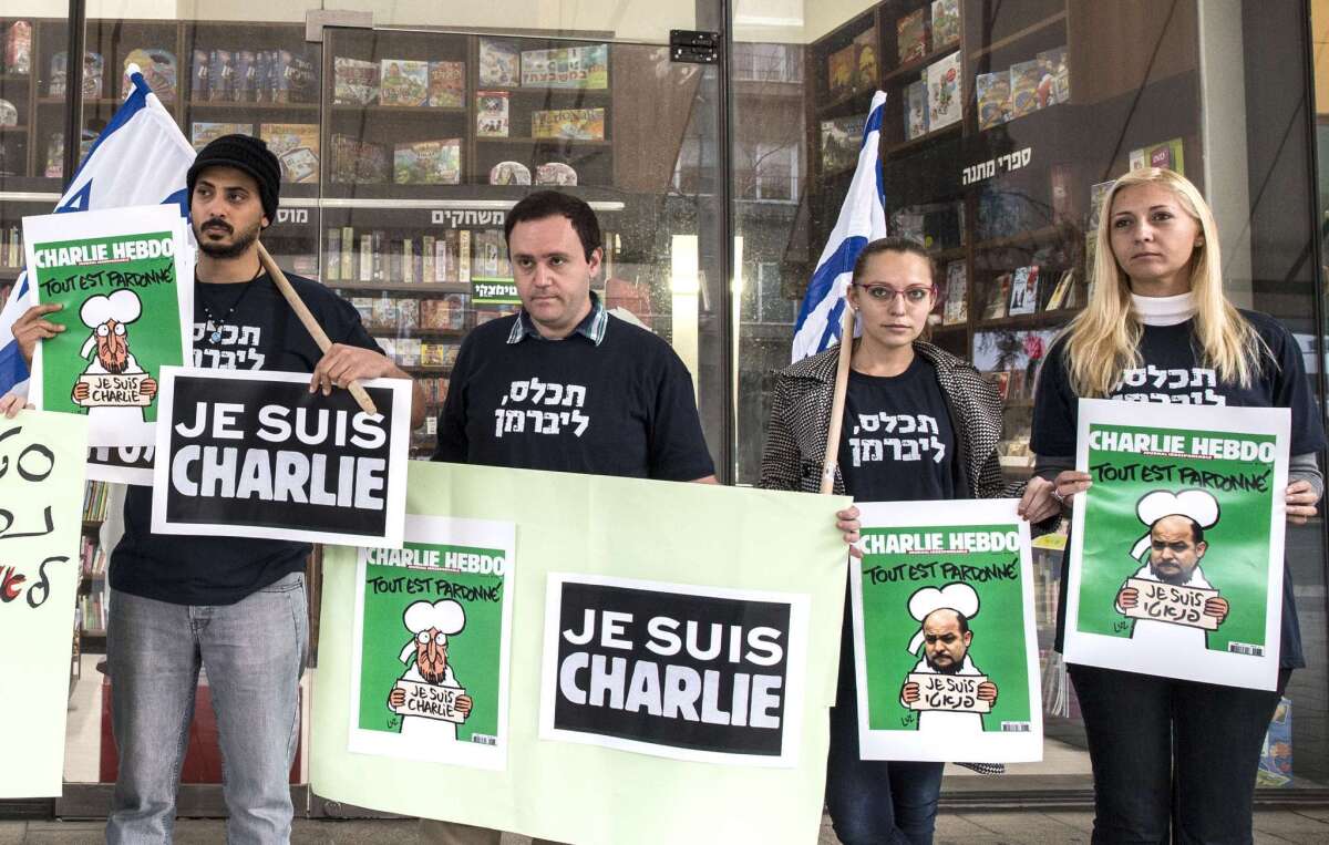 Israeli protesters hold copies of the latest edition of French satirical magazine Charlie Hebdo doctored to display portraits of Arab lawmaker Masoud Ghnaim, with a slogan that reads "I am fanatic," outside Steimatzky bookstore in Tel Aviv on Sunday.