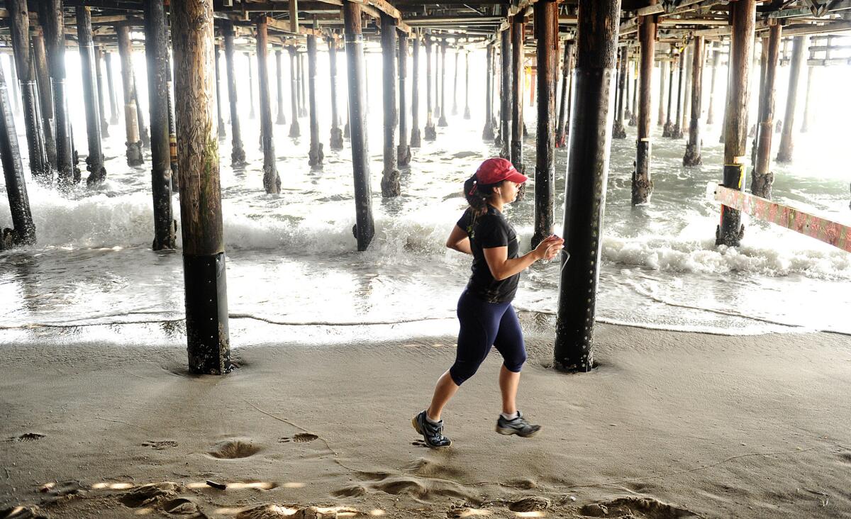 A jogger runs underneath the Santa Monica Pier in 2014. The beach at the pier was among the 10 worst-polluted "Beach Bummers" for 2016, along with Redondo Municipal Pier and Mother's Beach.
