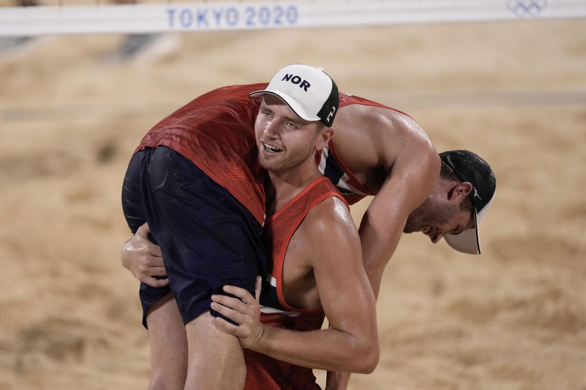 Anders Berntsen Mol, top, of Norway, is carried by teammate Christian Sandlie Sorum, celebrate winning a men's beach volleyball semifinal match against Latvia at the 2020 Summer Olympics, Thursday, Aug. 5, 2021, in Tokyo, Japan. (AP Photo/Petros Giannakouris)