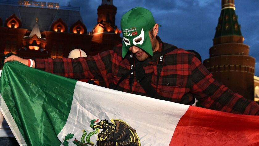 A fan of Mexico's national football team waves a Mexican flag as he cheers outside the Kremlin in Moscow ahead of the World Cup.