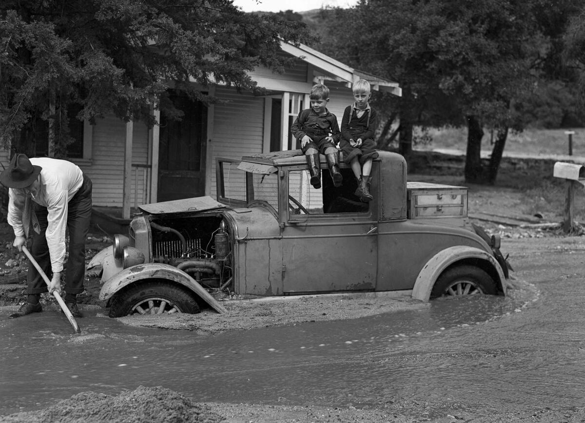 March 3, 1938: William L. Griffin begins shoveling mud to free the family car in the 1700 block of Fernlane Street as Lloyd Griffin and David Stagg watch.