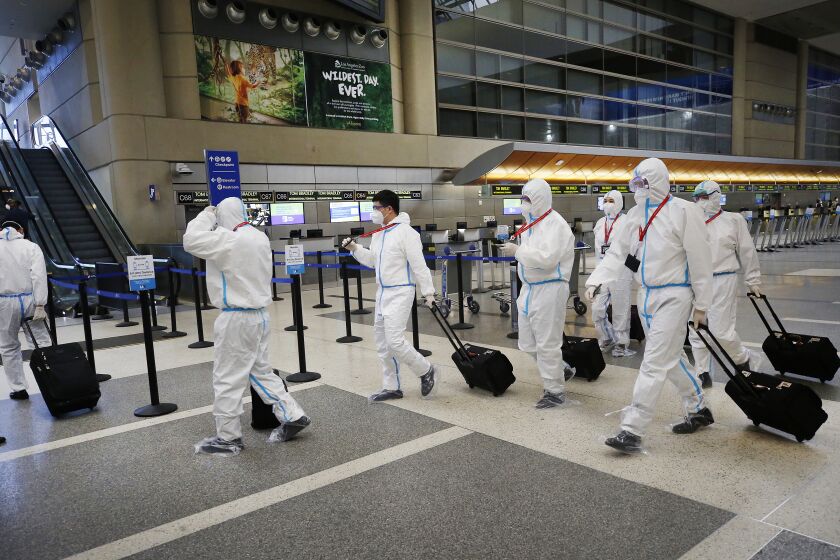 LOS ANGELES, CA - MAY 11: The flight crew for a Hainan Airlines flight walk through the Tom Bradley International Terminal, Los Angeles International Airport (LAX) which is now requiring travelers to wear face covering to help keep fellow passengers and crew safe by limiting the spread of the coronavirus Covid-19. The new requirements for wearing face masks in Los Angels began Monday at LAX and on local public transit. LAX on Monday, May 11, 2020 in Los Angeles, CA. (Al Seib / Los Angeles Times)