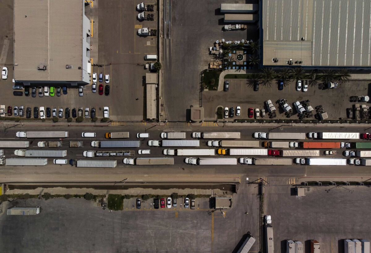 An aerial view of cargo trucks lined up on a road