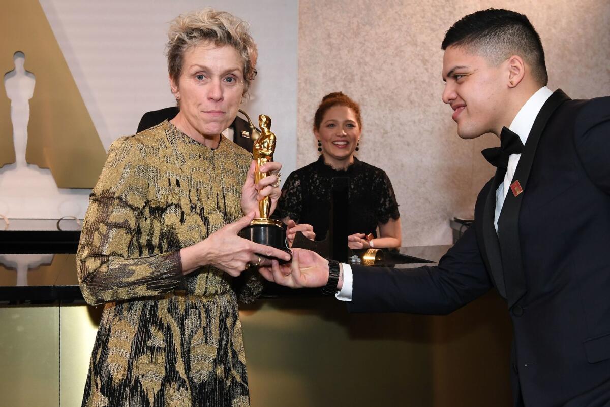 A happy Frances McDormand holds her freshly engraved Oscar at the Governors Ball following the Academy Awards, with her son Pedro by her side.