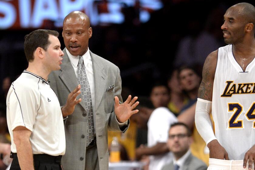 Lakers Coach Byron Scott and guard Kobe Bryant talk to referee Brian Forte before the start of overtime against the Raptors.