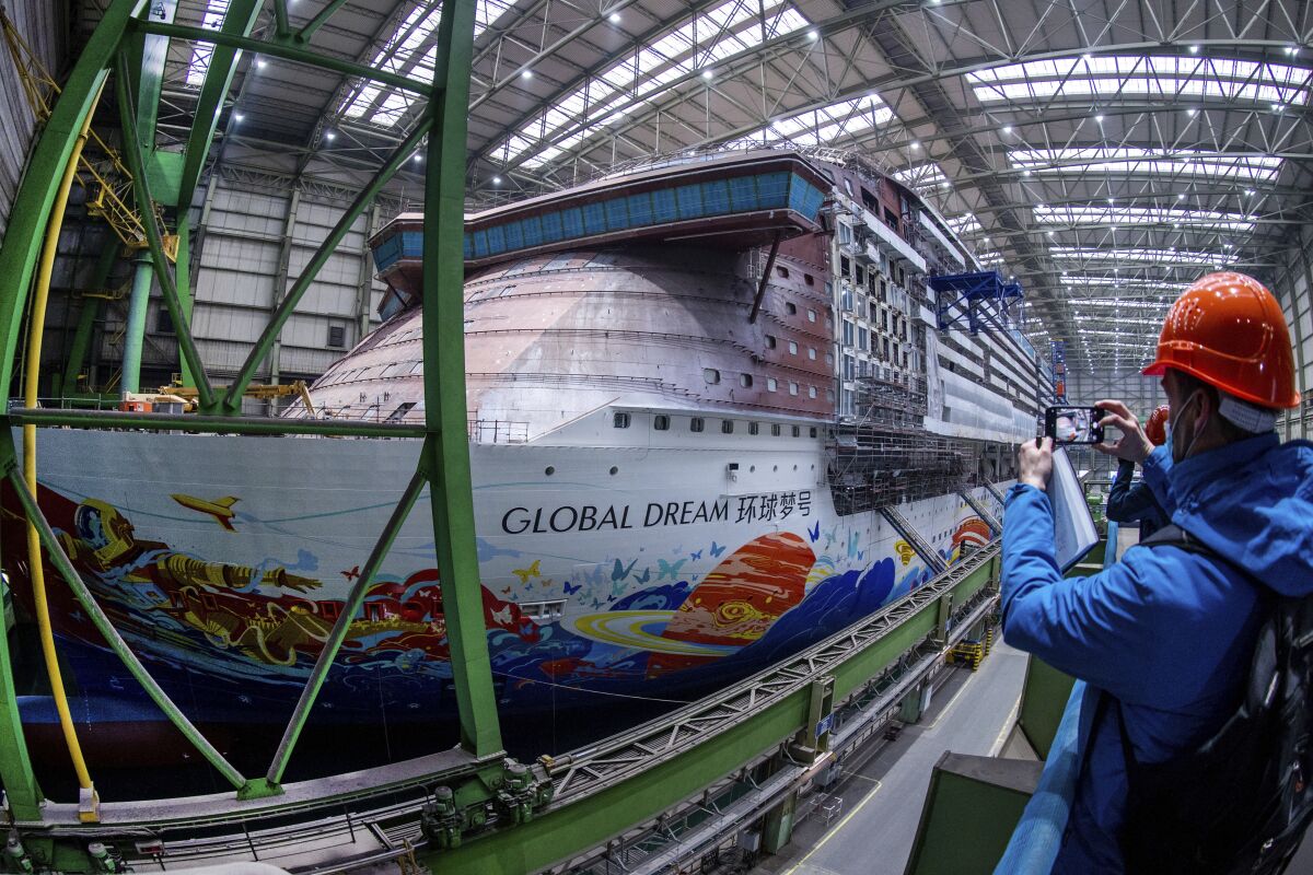 A media representative takes a photo of the cruise ship "Global Dream" under construction in the shipbuilding hall of MV Werften shipyard in Wismar, Germany, Friday, Jan. 7, 2022. The German government called on Malaysia-based Genting Group to contribute financially to the rescue of a shipyard it bought five years ago in northern Germany. German news agency dpa reported that the shipyard, MV Werften, filed for bankruptcy protection Monday, putting some 1,900 jobs at risk. ( Jens Buettner/dpa via AP)