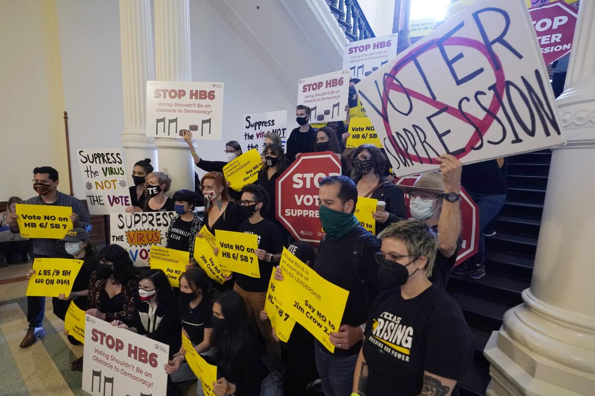 Crowd stands on steps holding signs