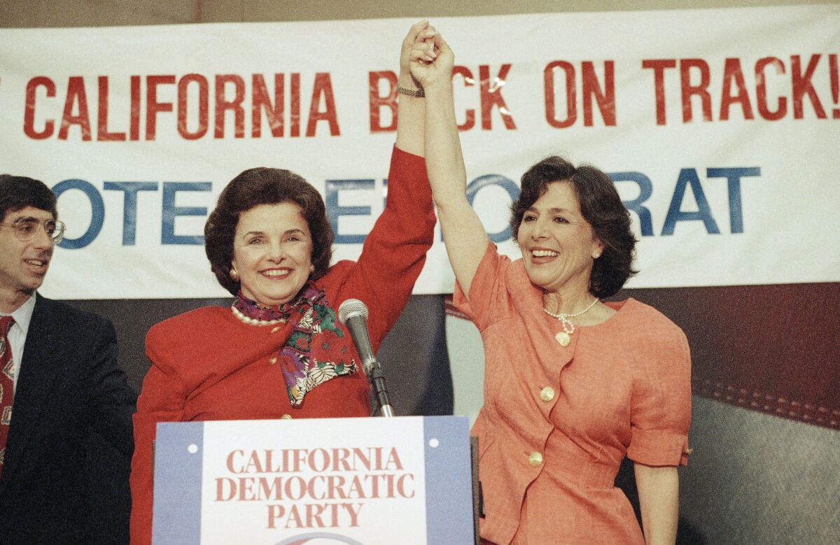 Dianne Feinstein, left, and Barbara Boxer raise their hands in victory.