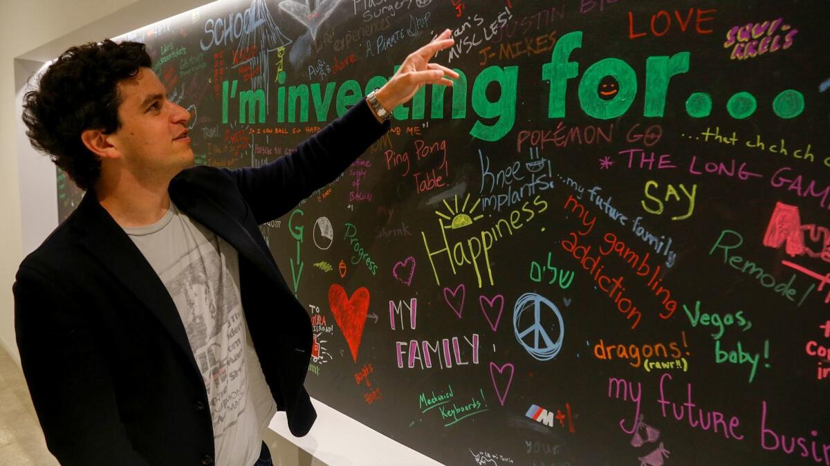 Noah Kerner, CEO of micro-investing firm Acorns, looks at a wall in the Irvine office where employees have written messages about their investment goals.