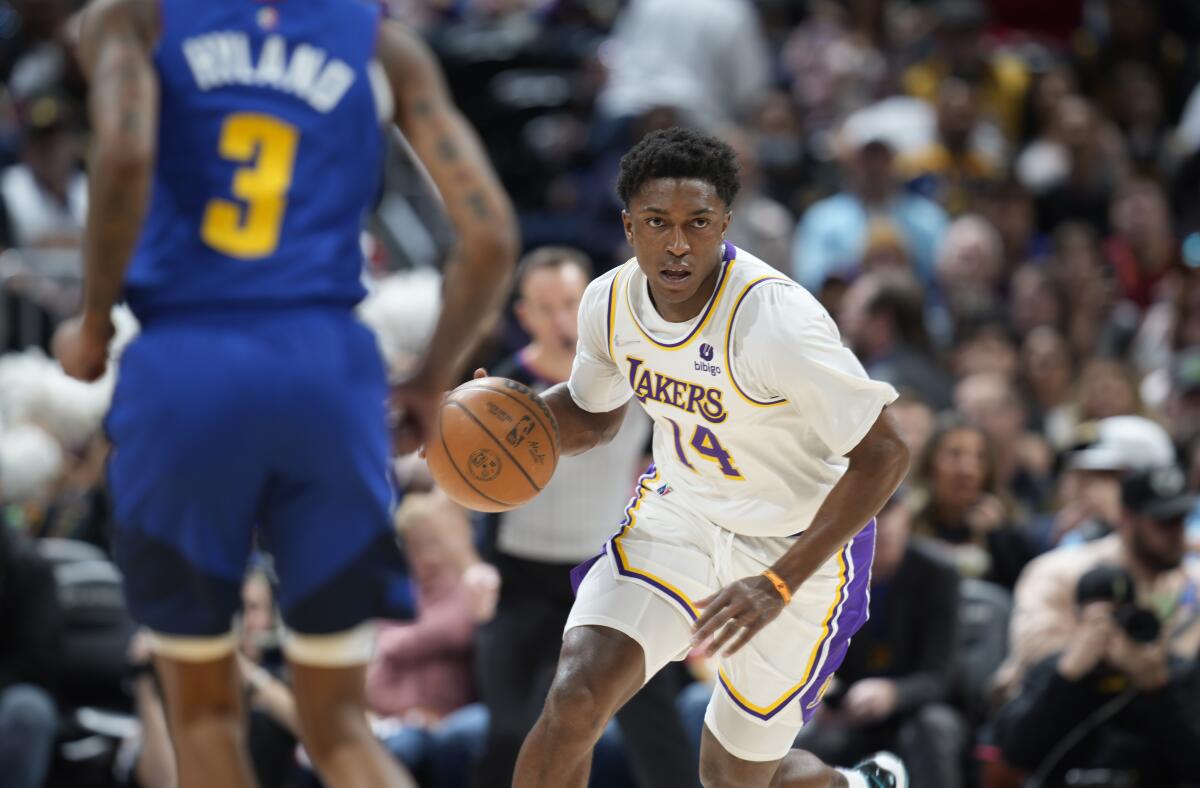 Lakers guard Stanley Johnson picks up a loose ball as Denver Nuggets guard Bones Hyland drops back to defend.
