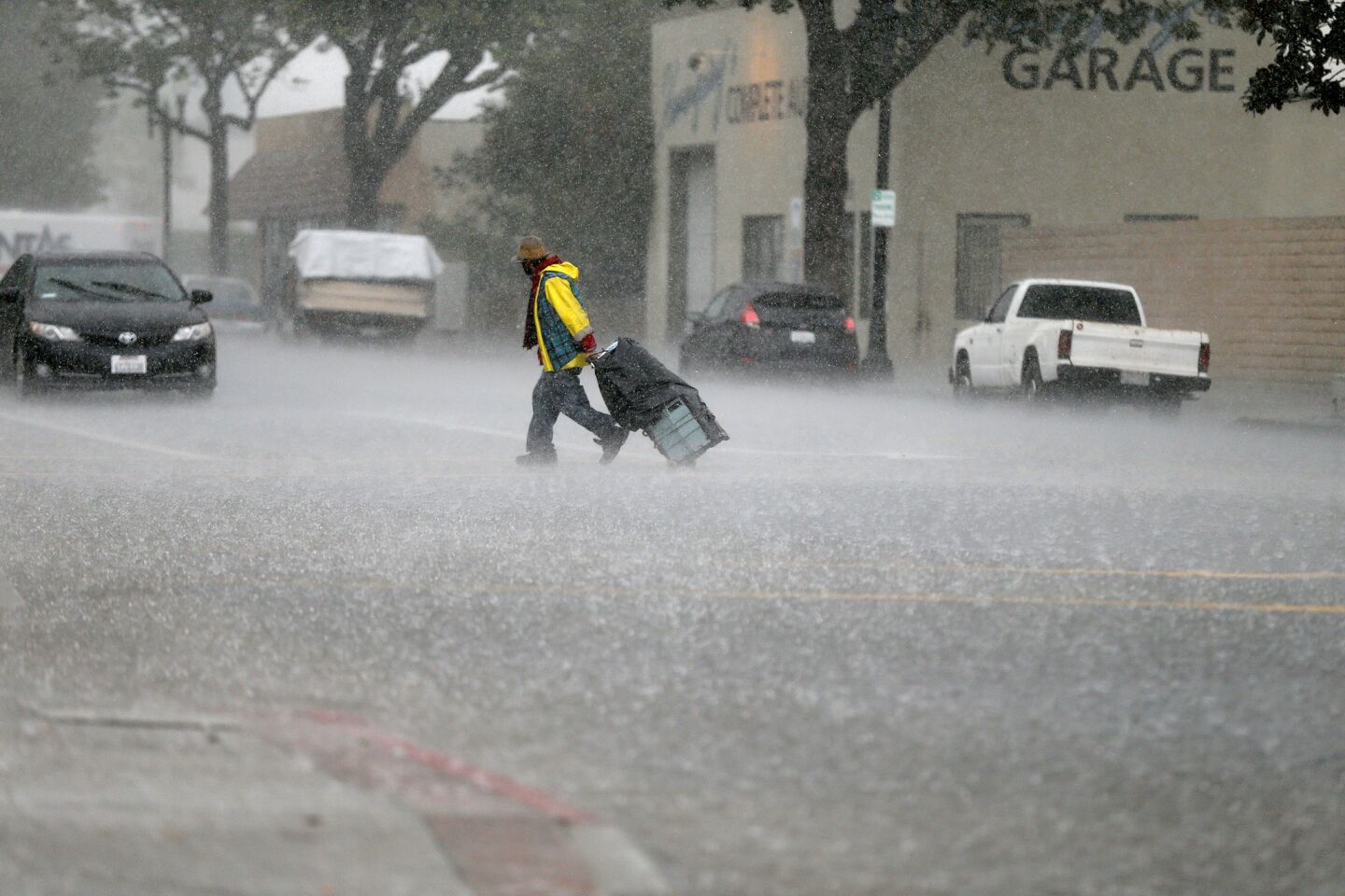 A man crossing the street gets caught in a heavy burst of rain on 4th Street in Santa Ana.