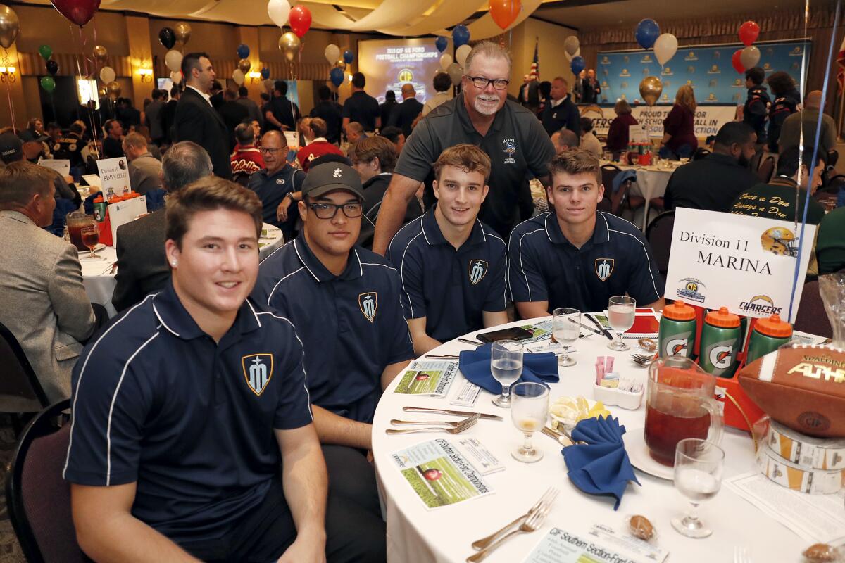 Marina coach Jeff Turley, standing, and players Nathan O'Rourke, left, Isaia Regan, Eric Church and Chase Hoglund attend the CIF Southern Section football championship luncheon on Monday at the Grand in Long Beach.