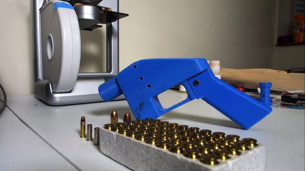 A Liberator pistol next to the 3-D printer on which its components were made, along with a box of ammunition.