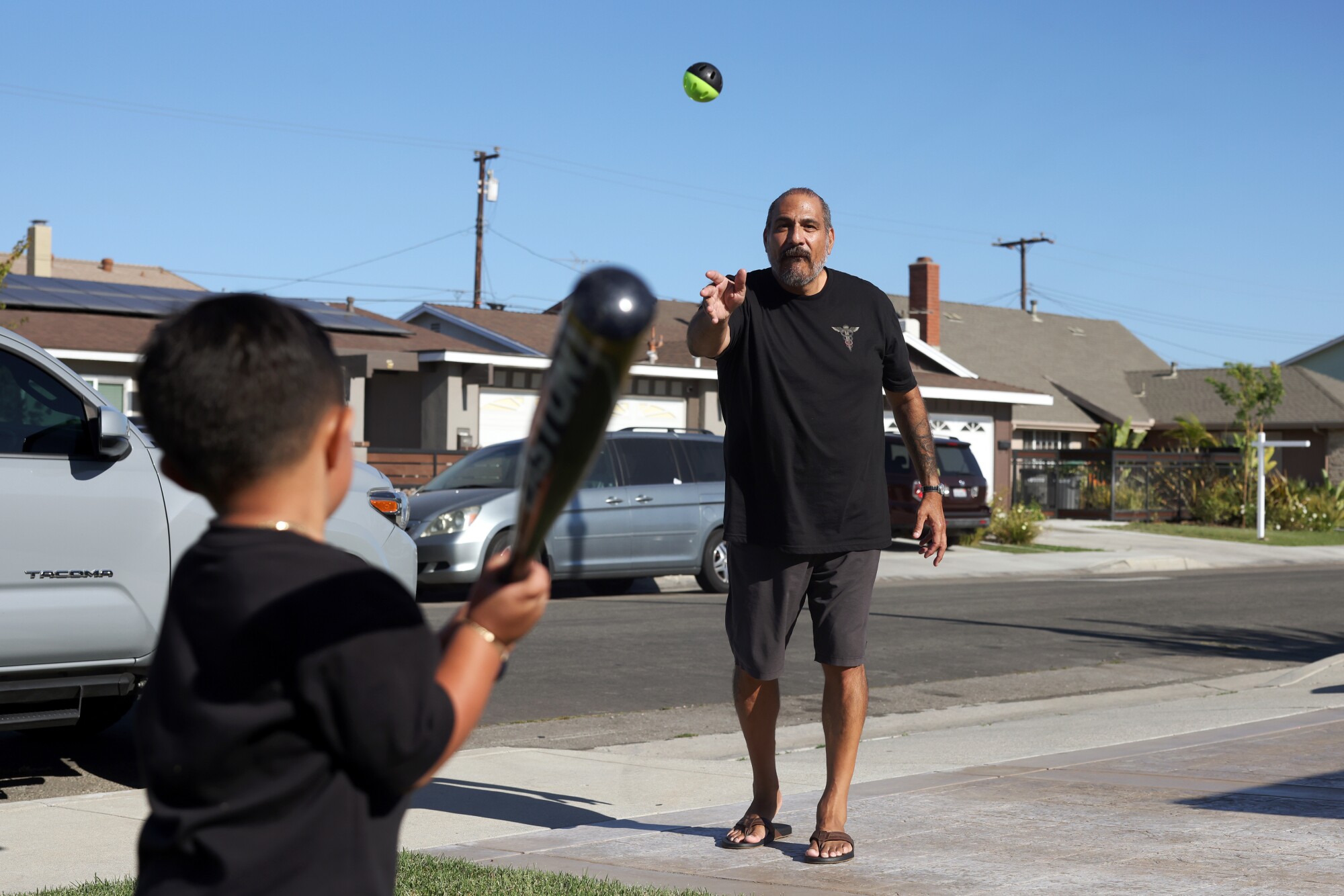 Chris Gutierrez, a former client of Girardi, plays toss with his grandson in the front yard of his home in Carson. 