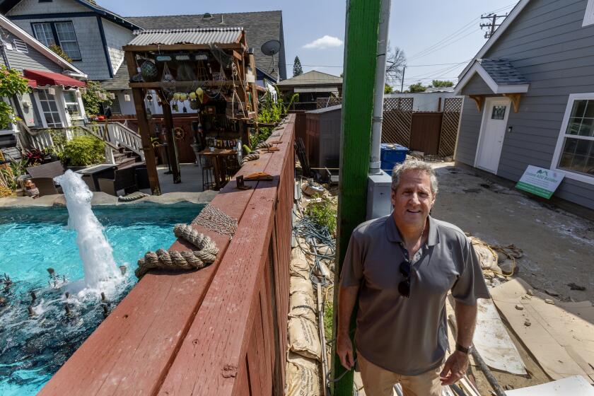 WHITTIER, CA - MAY 1, 2024: Whittier resident Sam Andreano stands next to the dividing wall with his old house on the left and his new home under construction on the right on May 1, 2024 in Whittier, California. Andreano took advantage of a new California law which allows homeowners to split their property in half.(Gina Ferazzi / Los Angeles Times)