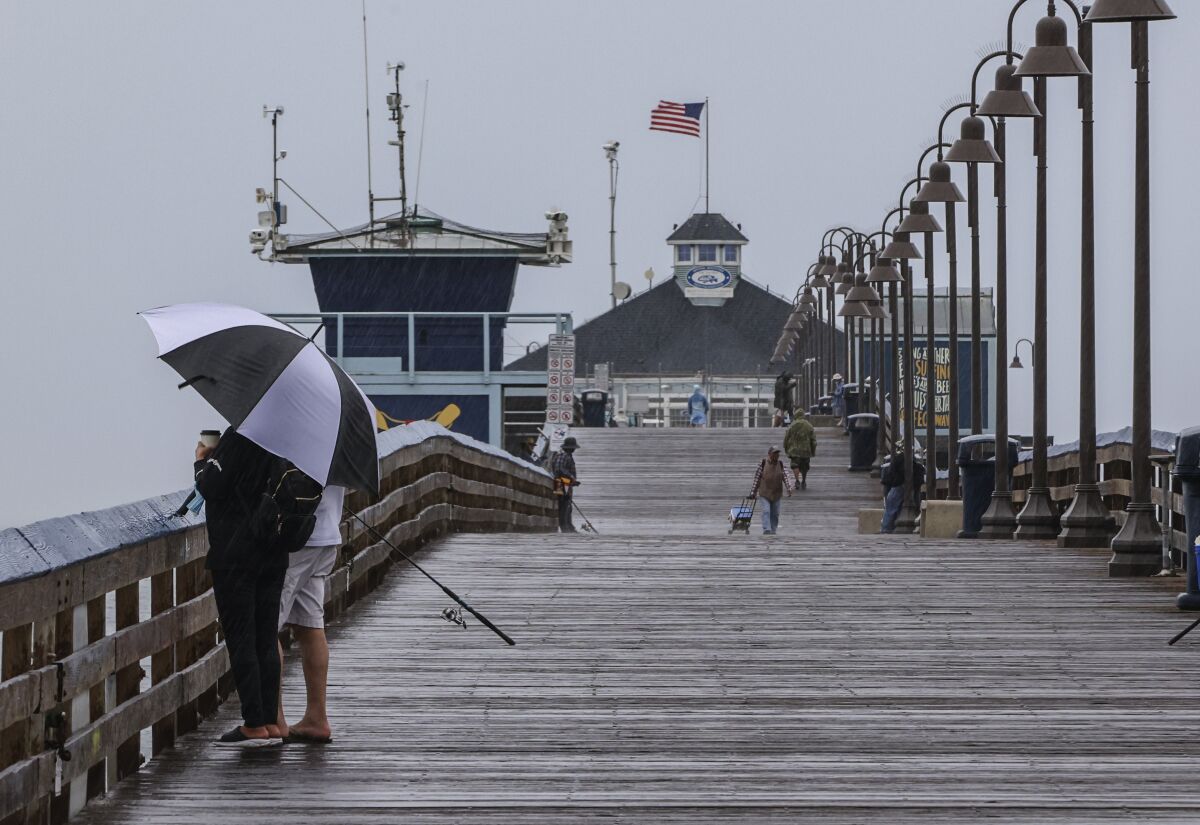 People at the Imperial Beach Pier take in the stormy weather.
