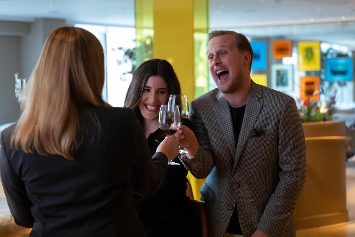 A man and two women toast with glasses of wine