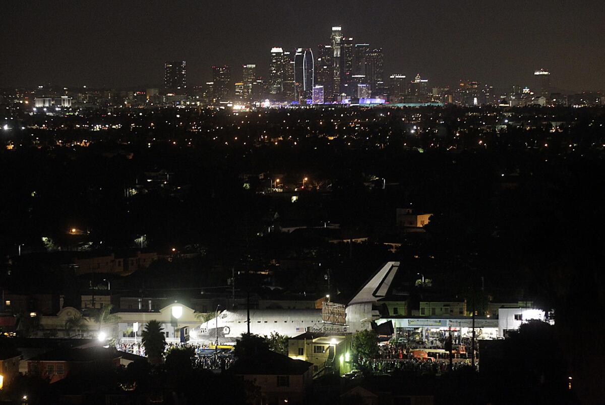 The Space Shuttle Endeavour is illuminated under a night sky as it moves slowly through the Crenshaw districct on its way to the California Science Center on Oct. 13, 2012.