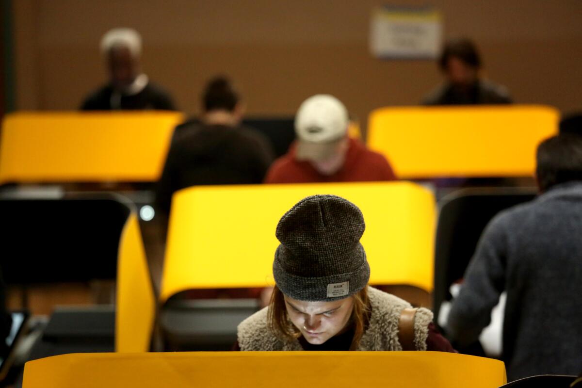 People are hunched over desks with yellow shields.