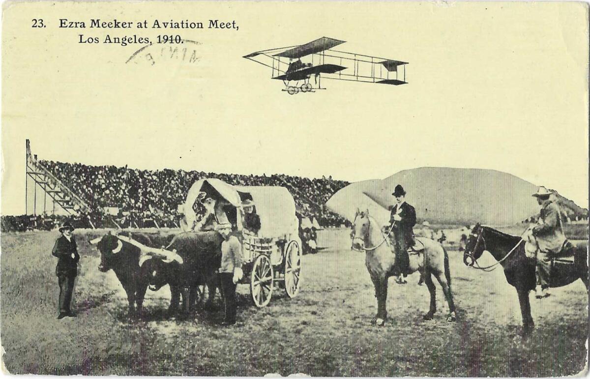 A sepia tone image shows a biplane above a grandstand, with an ox-drawn cart and men on horseback in the foreground.
