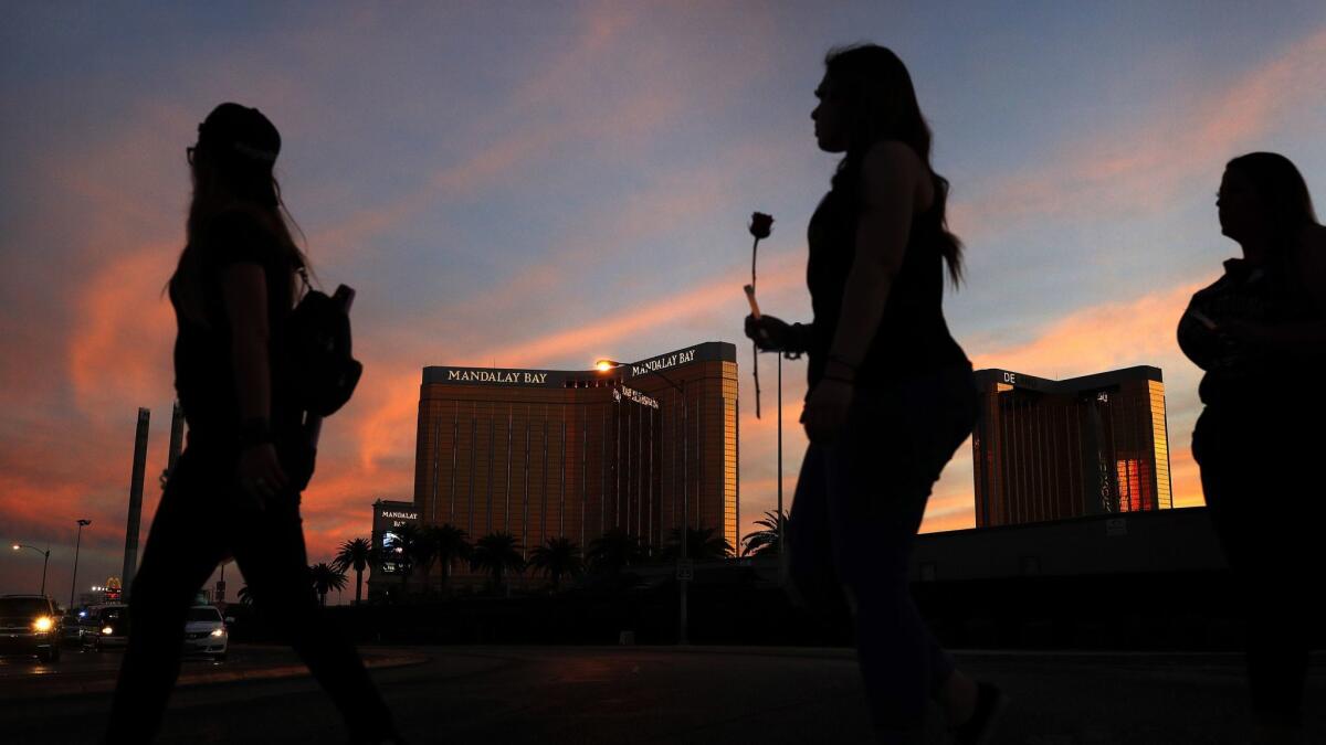 People carry flowers as they walk near the Mandalay Bay hotel and casino during a vigil for victims and survivors of a mass shooting in Las Vegas on April 1, 2018.