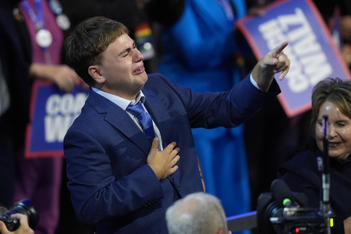 Gus Walz cries and points toward his father, Tim Walz, at the Democratic National Convention