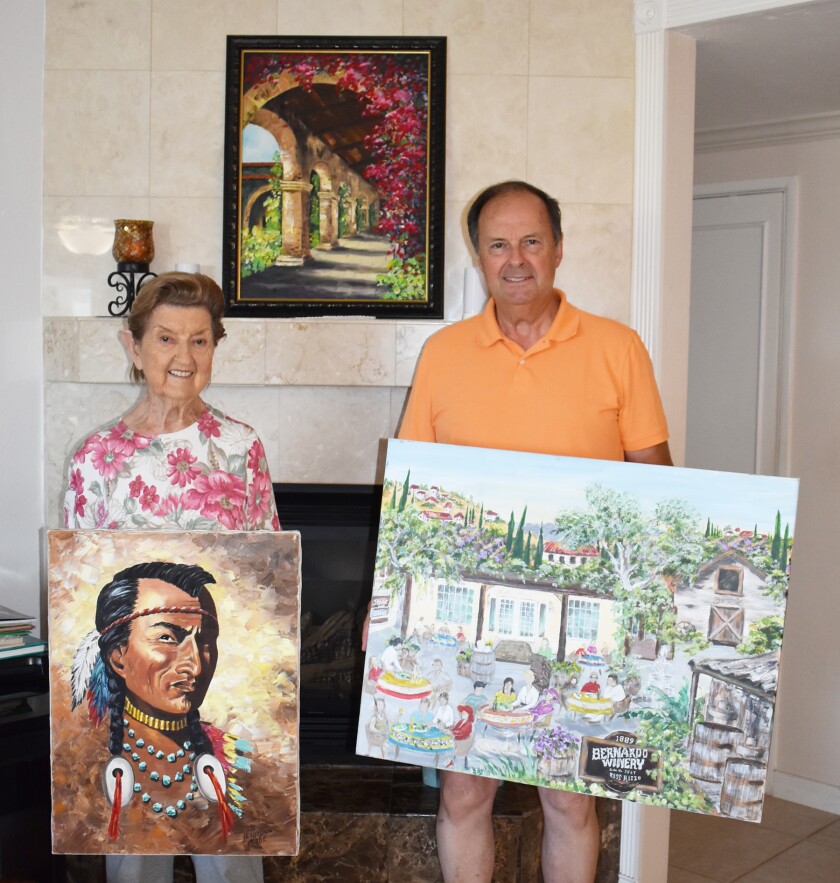 Rancho Bernardo resident Ellie Hodge, 92, and her oldest son, Grady Henderson, with some of her paintings.