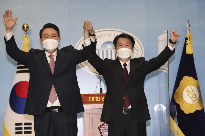 Presidential candidates Yoon Suk Yeol, left, of the main opposition People Power Party and Ahn Cheol-soo of the opposition People's Party raise their hands after a joint press conference at the National Assembly in Seoul, South Korea, Thursday, March 3, 2022. South Korea's two main opposition presidential runners agreed Thursday to field a unified candidate of them, a last-minute political deal ahead of next week's vote that could boost prospects for an opposition win to restore a conservative rule. (Lee Jung-hoon/Yonhap via AP)