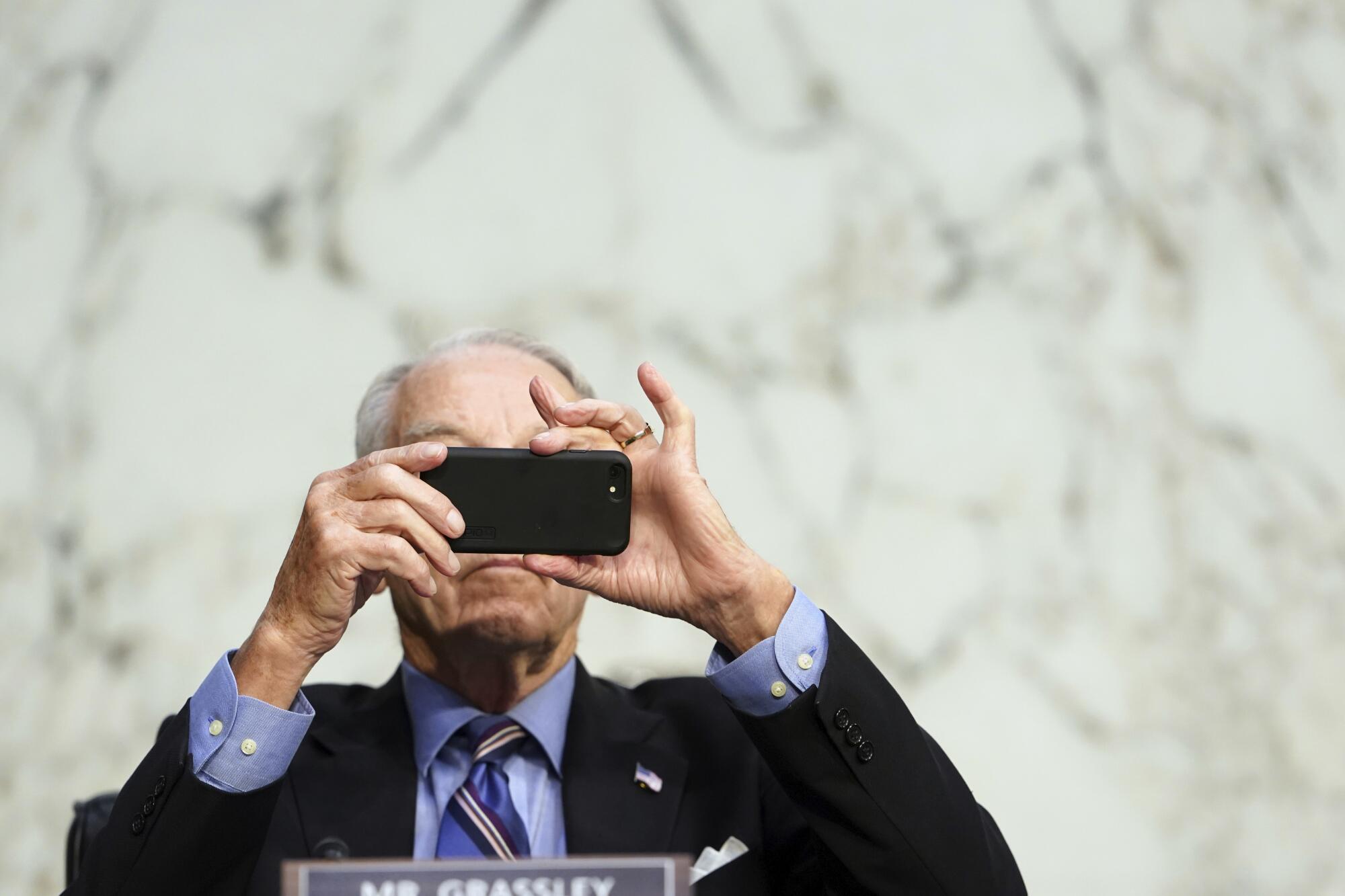 Sen. Charles Grassley appears to be taking a photo with his phone before the hearing.