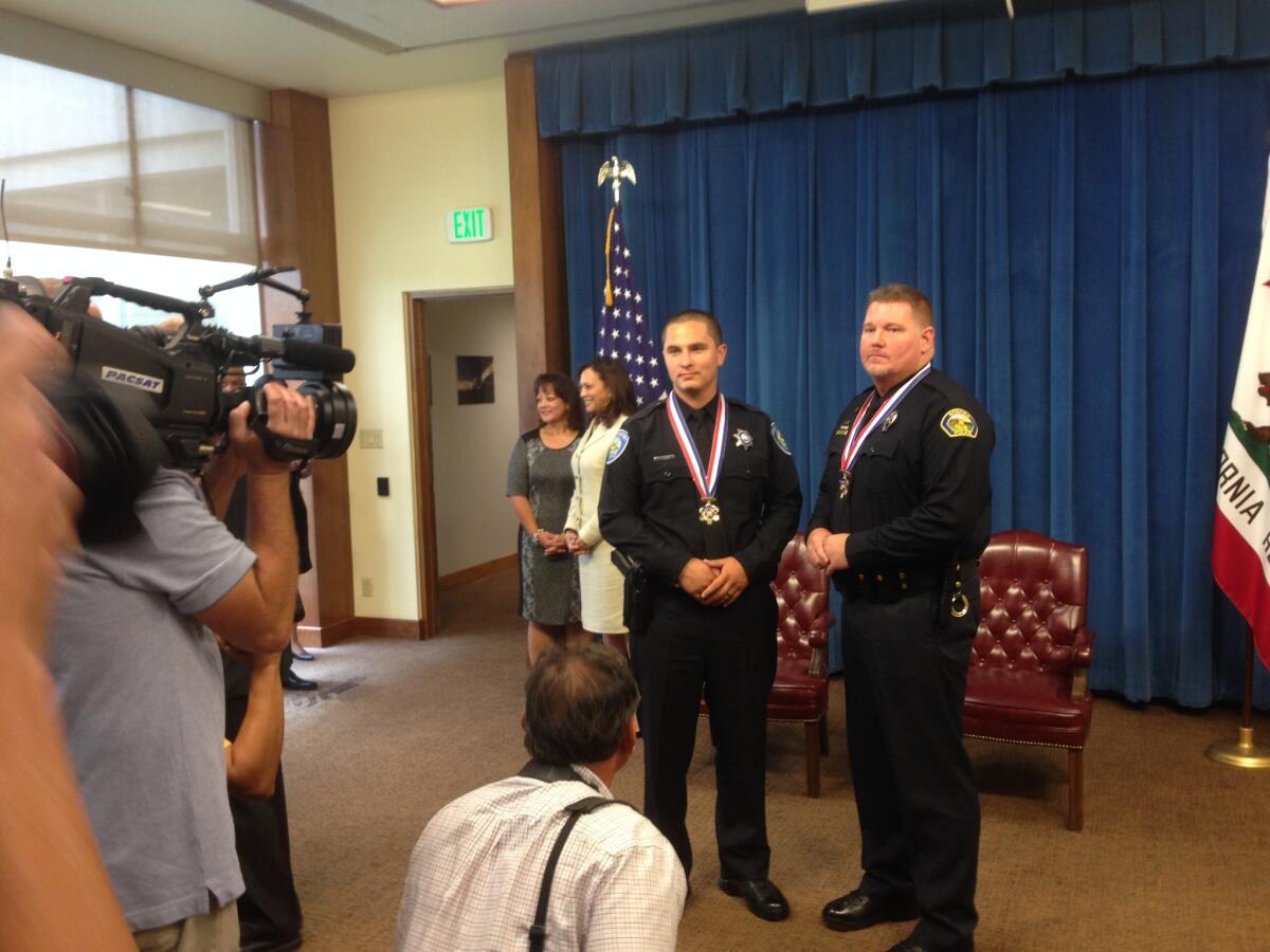 San Bernardino Police Officer Marcus Pesquera, left, and Sonora Police Officer Ryan D. Webb post for photos at the state Capitol after being awarded the state's Medal of Valor by Gov. Jerry Brown.