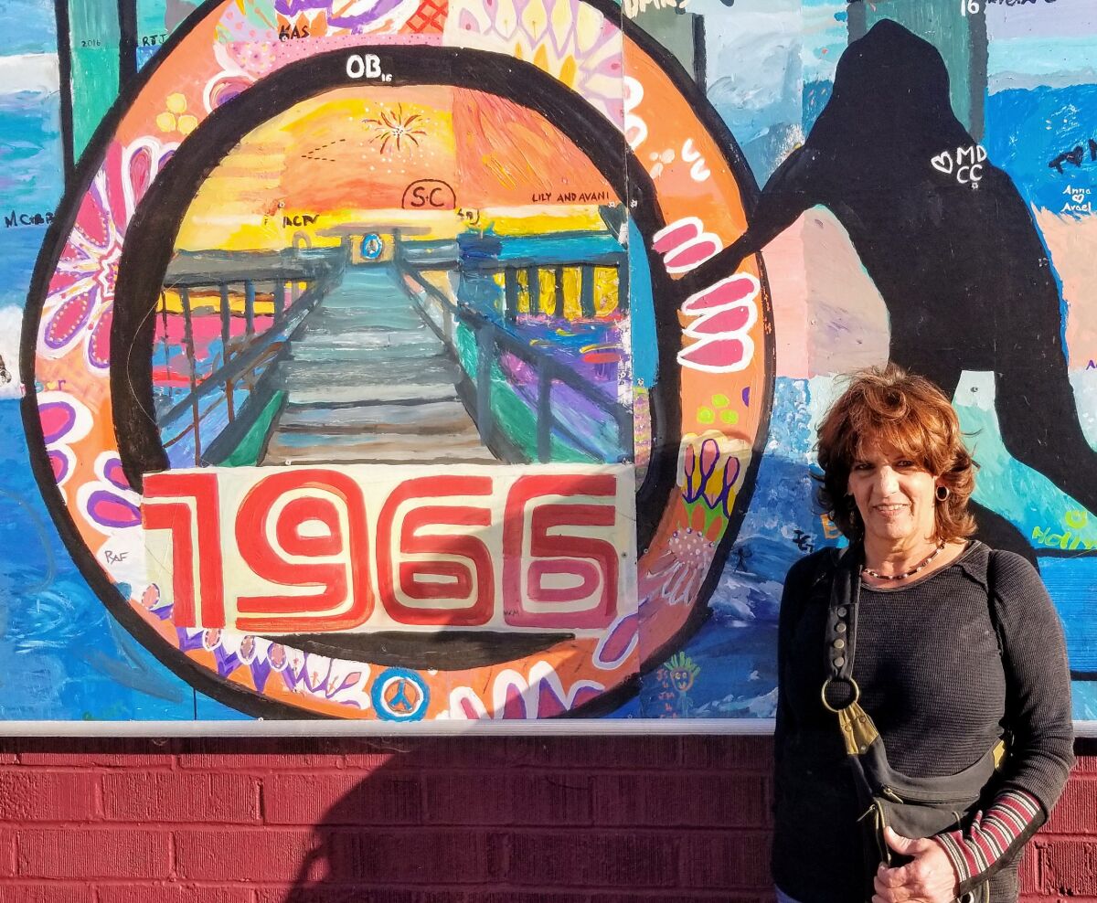 Artist Janis Ambrosiani poses with one of the many OB murals.