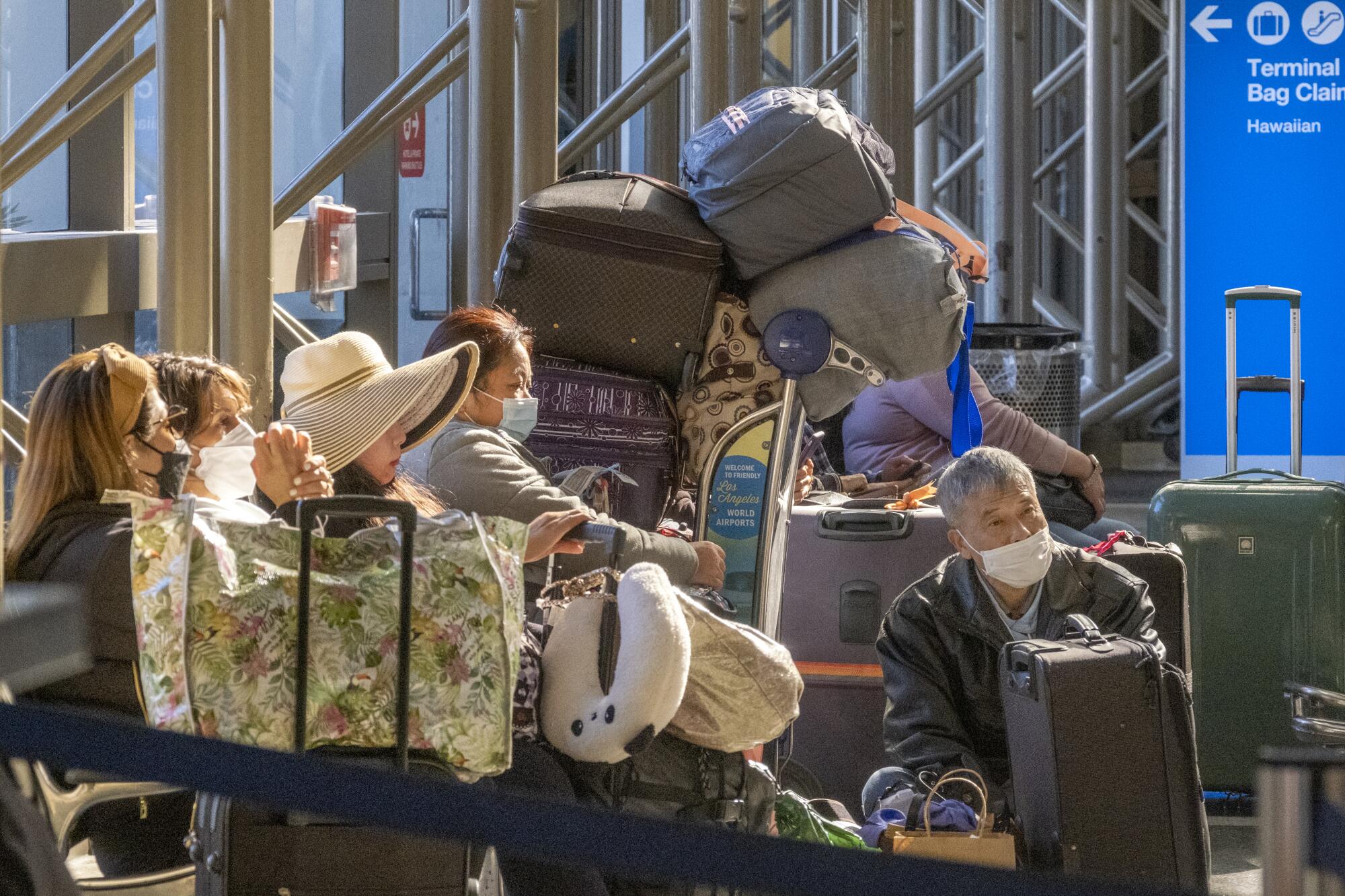 Travelers wait at Tom Bradley International Terminal on Sunday