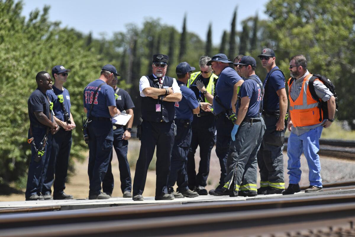 An Amtrak conductor and emergency workers standing on train tracks