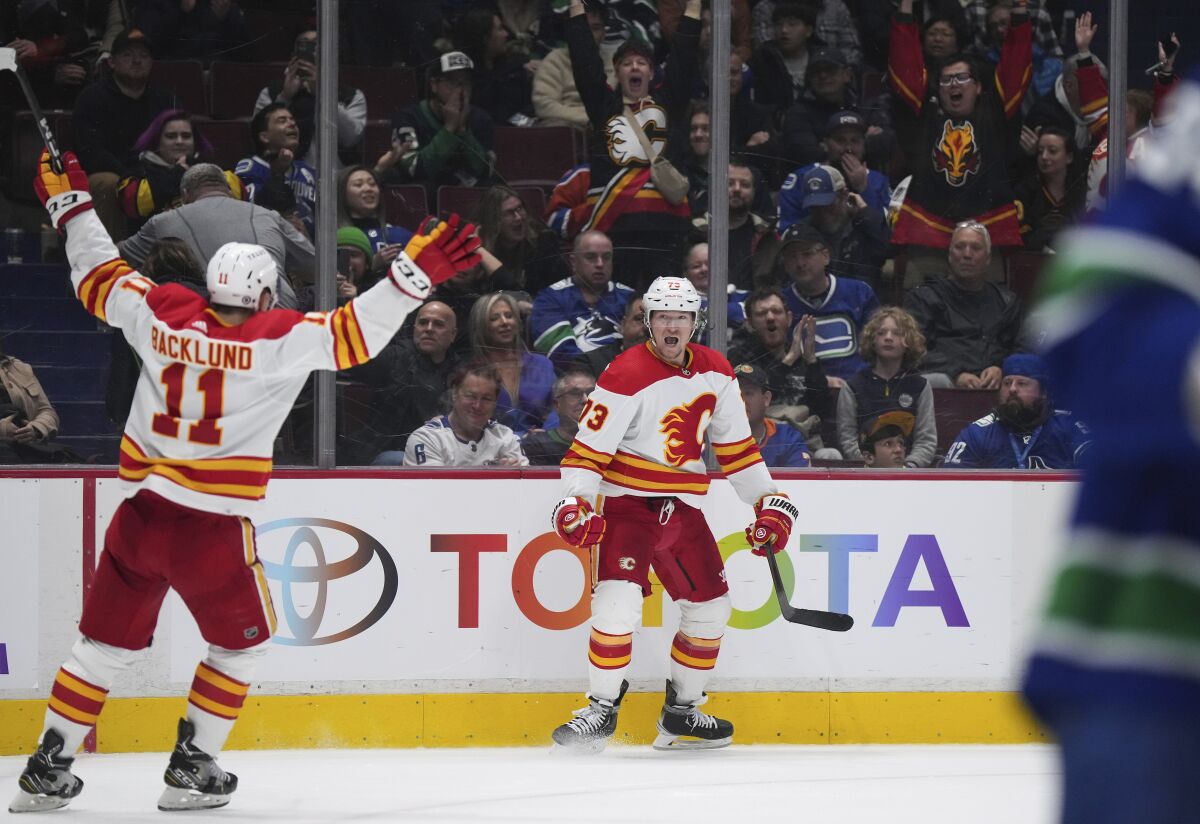 Calgary Flames' Tyler Toffoli, center, and Mikael Backlund celebrate Toffoli's overtime goal against the Vancouver Canucks in an NHL hockey game Friday, March 31, 2023, in Vancouver, British Columbia. (Darryl Dyck/The Canadian Press via AP)