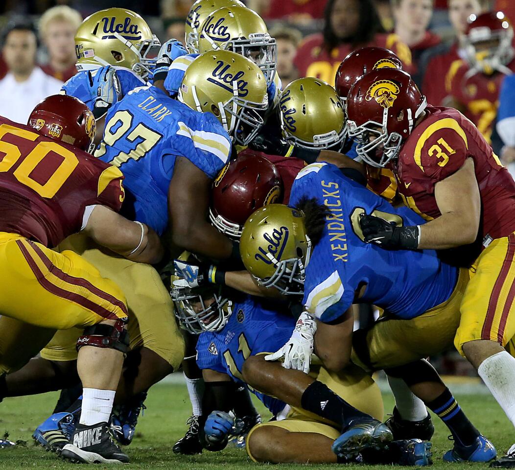 Trojans tailback Javorius Allen, center, is swarmed by the UCLA defense during the fourth quarter of a game on Nov. 30, 2013.