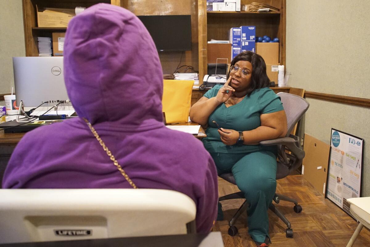 A nurse speaks to a patient, both of them seated in an office