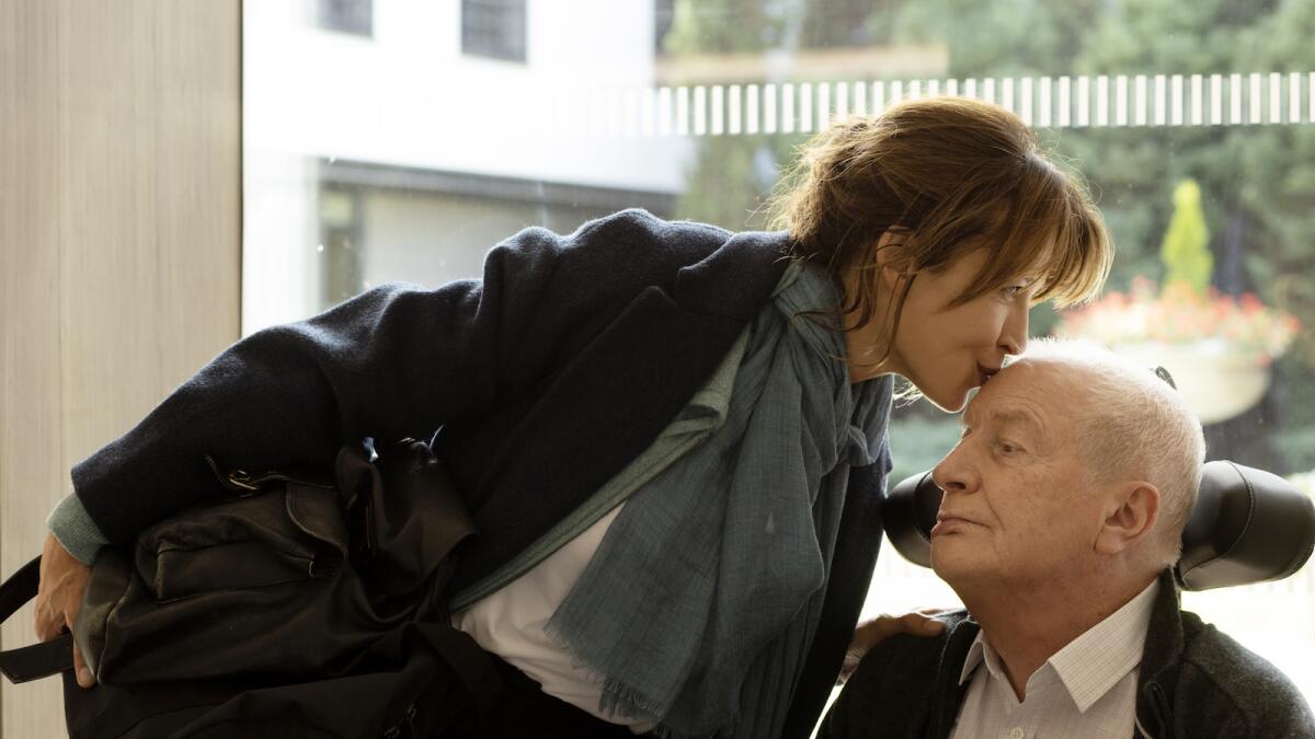A woman kisses the top of her elderly father's head in a scene from "Everything Went Fine."