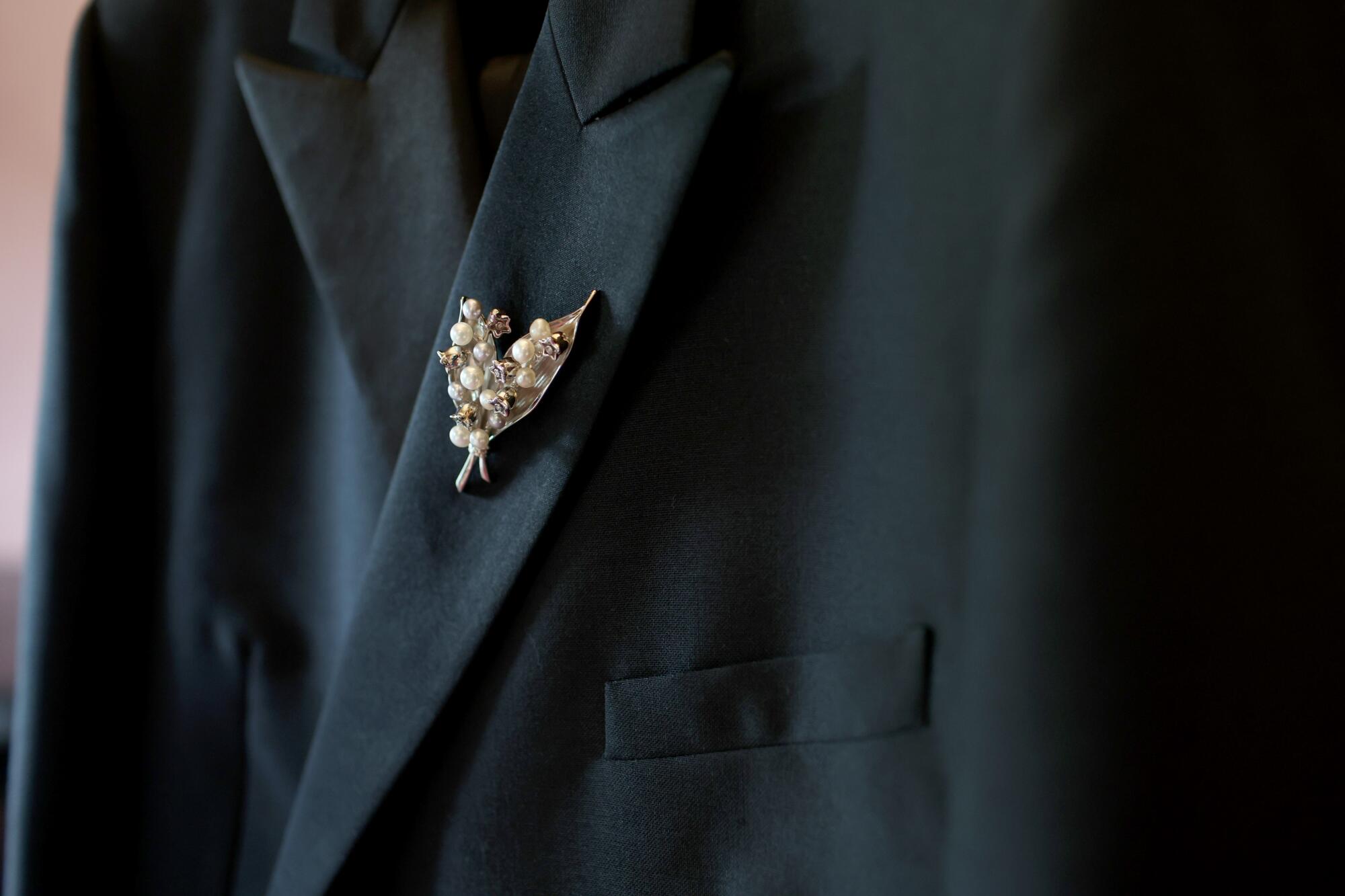 A black coat with a white pearl lily broach.