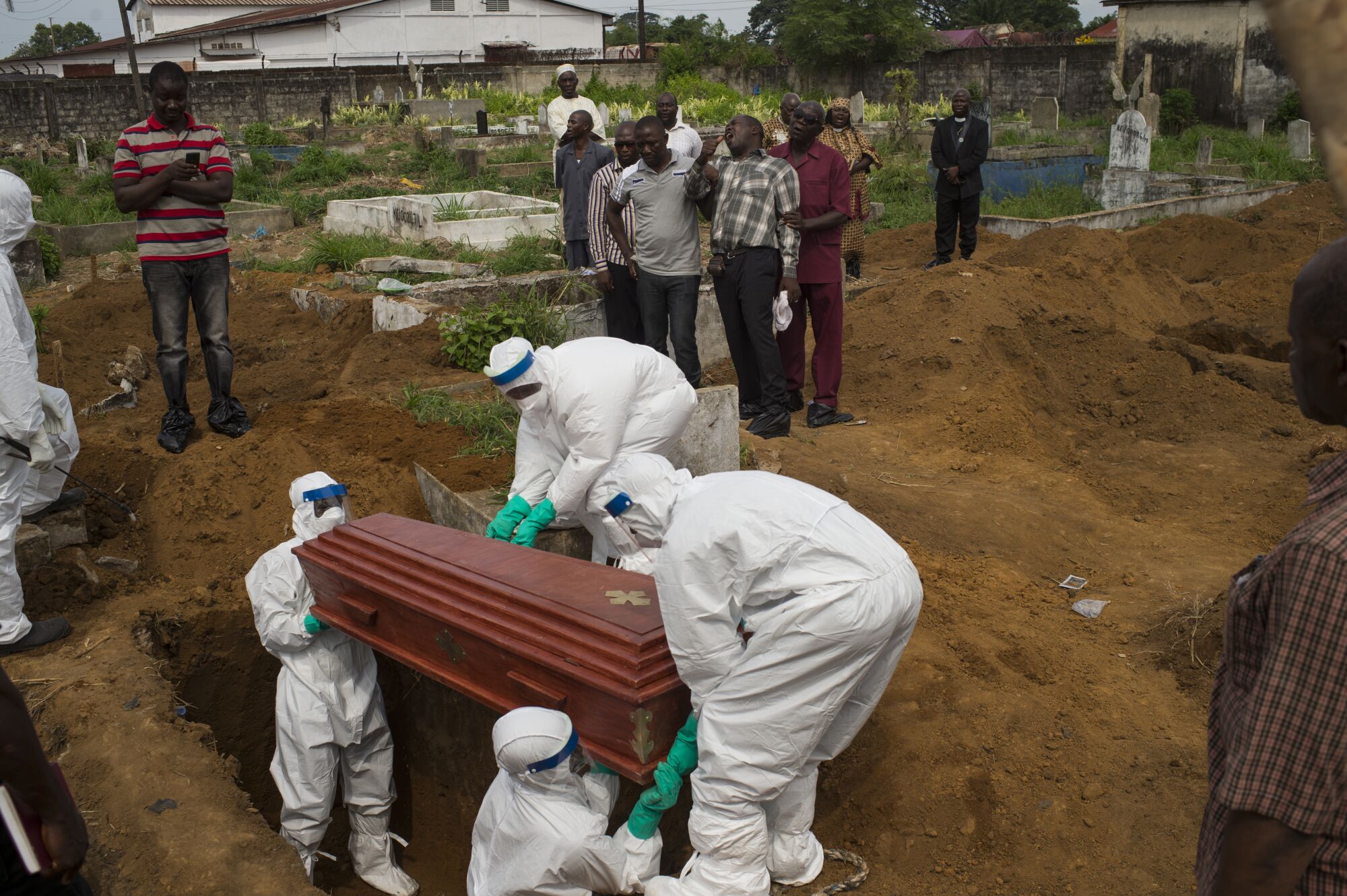 Workers in hazmat suits lower a coffin into a grave in Freetown, Sierra Leone, in 2014.