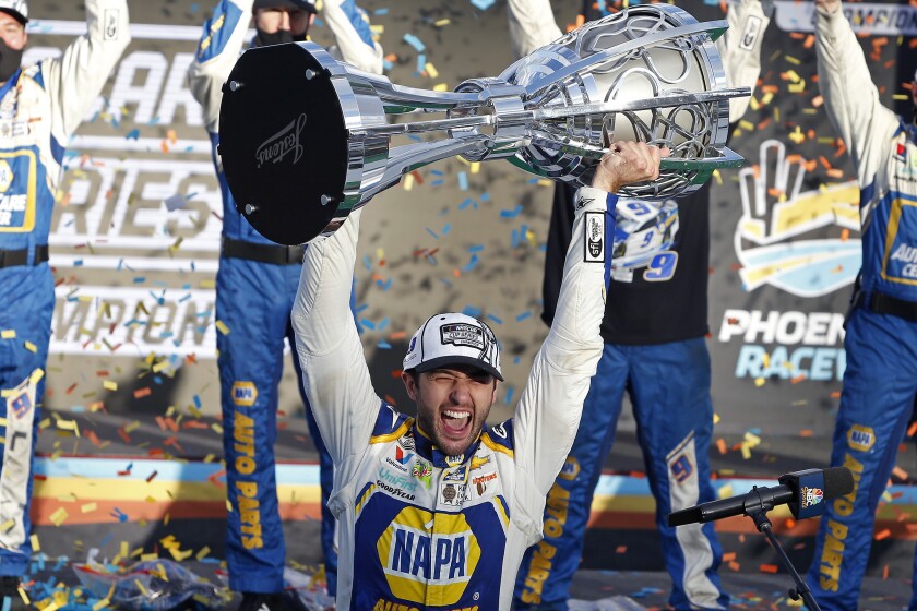 FILE - Chase Elliott holds up the season championship trophy as he celebrates with his race crew in Victory Lane after winning the NASCAR Cup Series auto race at Phoenix Raceway in Avondale, Ariz., in this Sunday, Nov. 8, 2020, file photo. NASCAR is being heavily promoted by a broadcast partner as about to embark on “The Best Season Ever” and on paper that could be true. NASCAR this year will race on dirt for the first time since 1970, the schedule includes a whopping seven road courses and five venues new to the Cup Series. Michael Jordan and Pitbull are among new team owners entering the sport in 2021 and Chase Elliott, NASCAR’s most popular driver, is the reigning champion. (AP Photo/Ralph Freso, File)