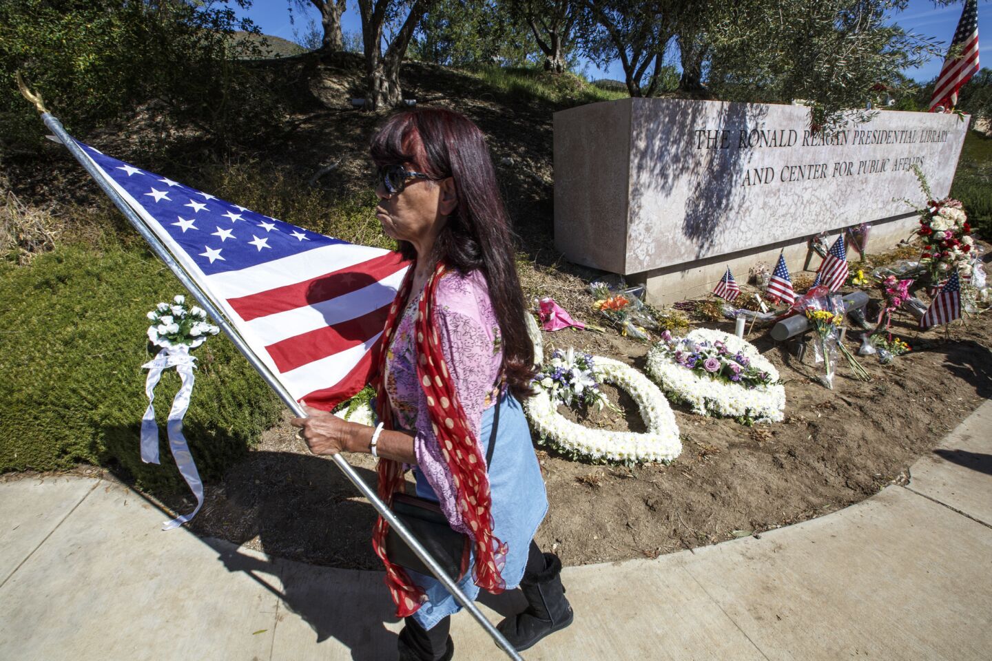 Flags and flowers are placed at the entrance to the Ronal Reagan Presidential Library as people wait for the motorcade bringing Nancy Reagan's body to lie in repose.
