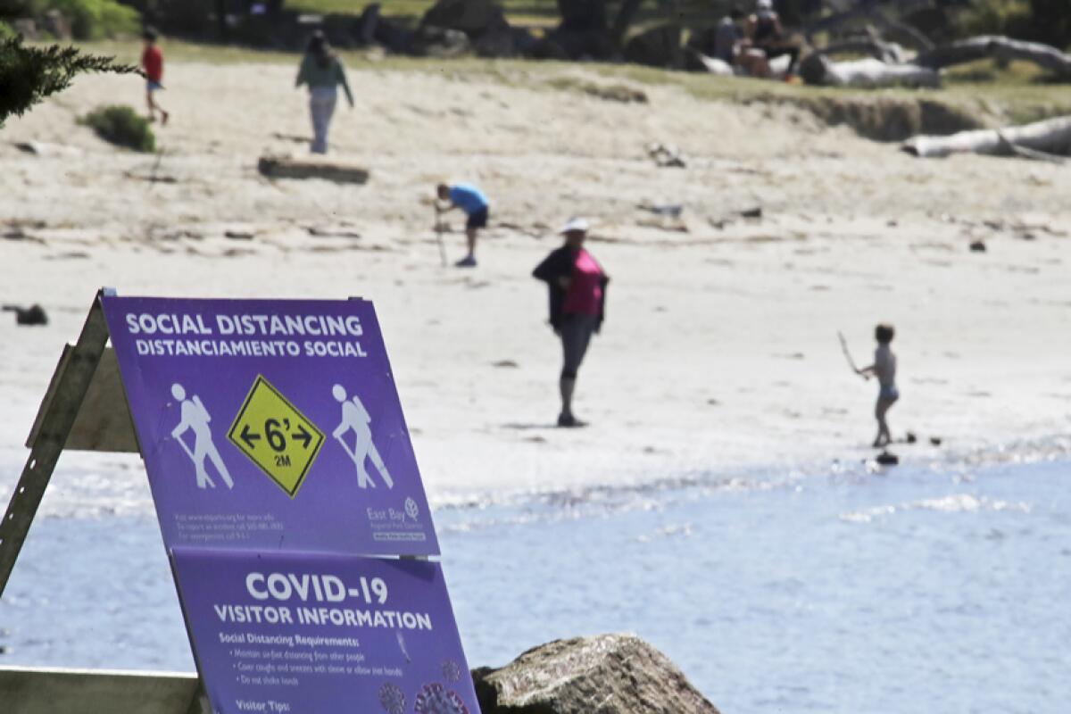A sign encourages visitors to keep their distance from one another at Crab Cove in Alameda, Calif.