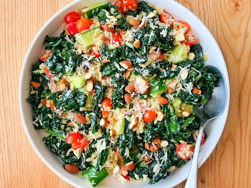 A bowl of salad with kale, cherry tomatoes, almonds and other vegetables.