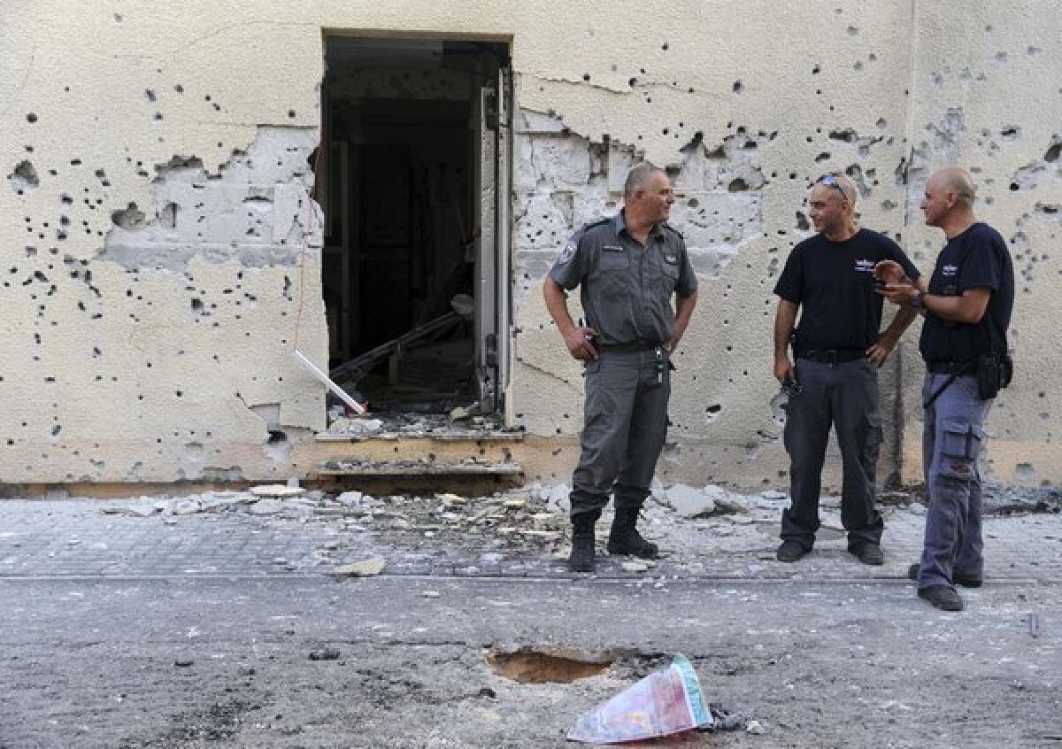 Israeli policemen on Thursday stand in front of a house damaged by a rocket fired from Lebanon in Moshav Shavei Zion, Israel.