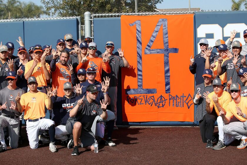 Members of the Orange Coast College baseball team and coaches, gather around a homemade banner in honor of head baseball coach John Altobelli, who perished with wife Keri, and daughter, Alyssa, in Sunday's helicopter crash with Kobe Bryant.