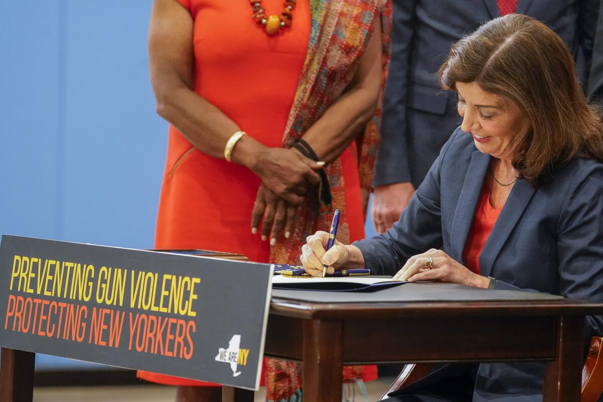 A woman sitting at a desk signs a piece of paper.