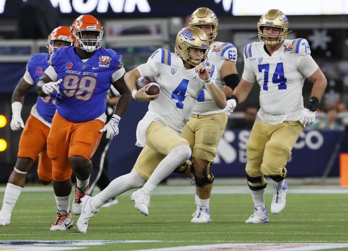 UCLA quarterback Ethan Garbers scrambles for a first down while getting chased by Boise State players.